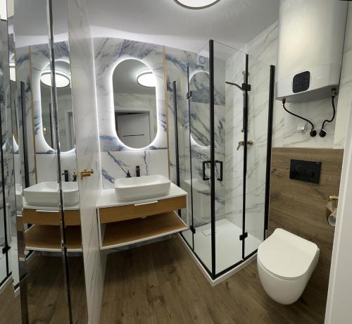 La salle de bains est pourvue de 2 lavabos, d'une douche et de toilettes. dans l'établissement Apartament przy morzu W22, à Rowy