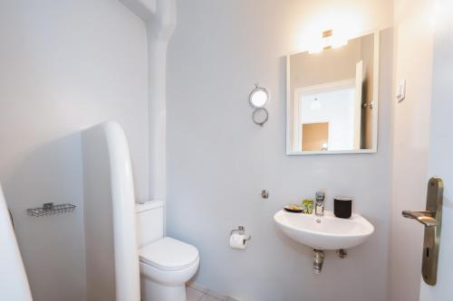 a white bathroom with a toilet and a sink at Anzuelo Apartments in Megalochori