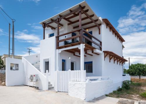 a white house with a wooden roof at Anzuelo Apartments in Megalochori