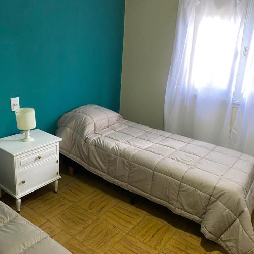 a bedroom with a bed and a nightstand and a window at Hosteria Tobago in Necochea