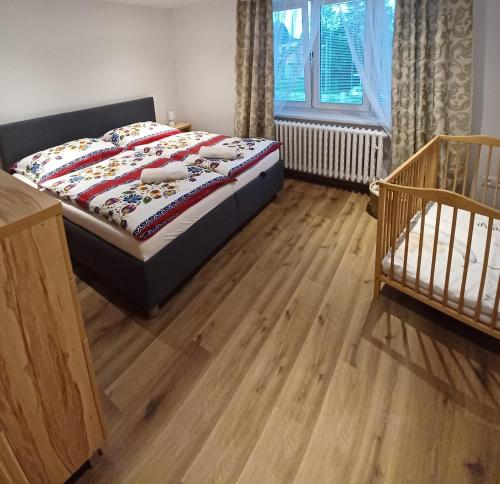 1 dormitorio con 1 cama y suelo de madera en Apartmán 4M Tatry, en Tatranská Štrba