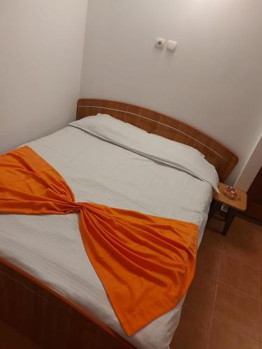 Una cama con una manta naranja encima. en Legend Room en Pucioasa