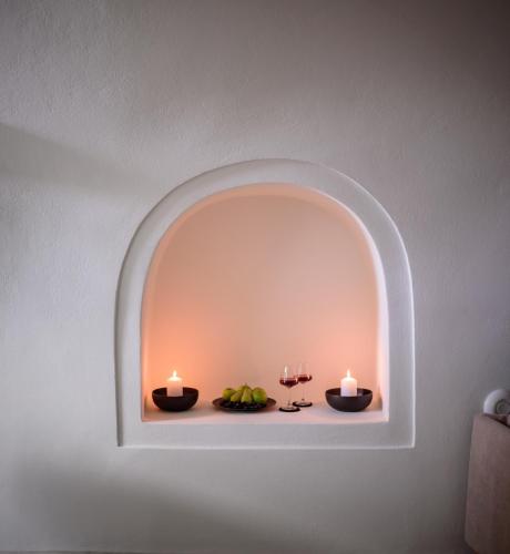 an arched niche with two candles on a wall at Aethria Villa in Imerovigli