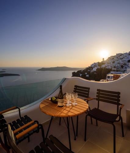 a table and chairs on a balcony with a view at Aethria Villa in Imerovigli