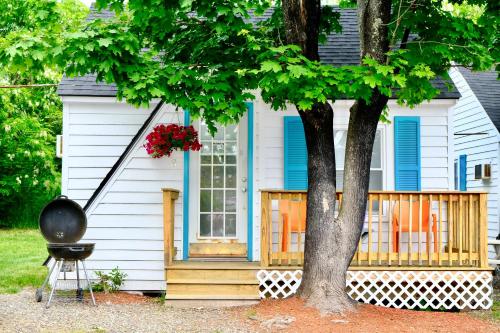 a house with a tree and a grill in front of it at The Landings Inn and Cottages at Old Orchard Beach in Old Orchard Beach