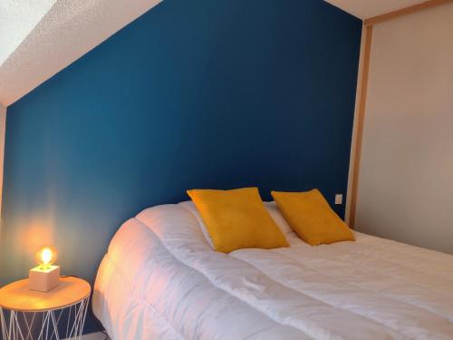 a blue bedroom with a bed with two yellow pillows at L'incontournable, centre ville parking wifi linge de maison fourni in Vannes