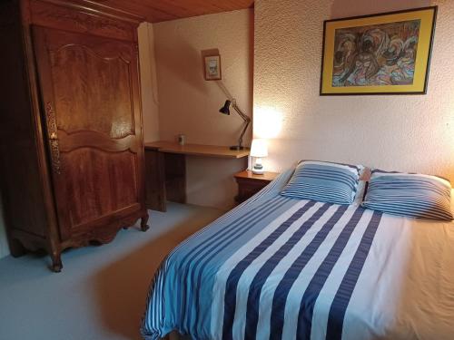 a bedroom with a bed with a blue and white striped blanket at Calme et verdure in Buxerolles