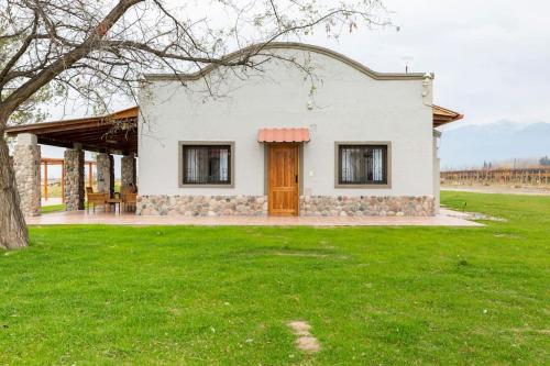 a white house with a tree and a green field at Calivista Vineyard in Tunuyán