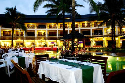 a restaurant with tables and chairs and a building at Khaolak Orchid Beach Resort - SHA Extra Plus in Khao Lak