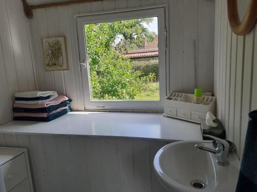 uma casa de banho com um lavatório e uma janela em Rüdiger, der Bauwagen am Deich. 