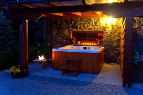 a jacuzzi tub sitting under a stone wall at Villa Bezycer in Gowidlino