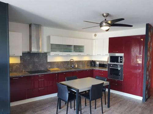 une cuisine avec des placards rouges et une table avec des chaises dans l'établissement Marina La Plagette RDC appontement XL parking, au Grau-du-Roi