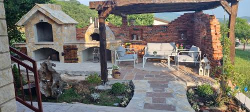a backyard patio with an outdoor fireplace and a brick wall at Villa Emili in Posušje