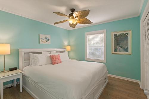 ein Schlafzimmer mit einem weißen Bett und einem Deckenventilator in der Unterkunft The Seaclusion Top Floor - 300 Seventh Street in Saint Simons