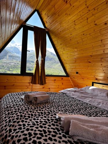 a bed in a room with a large window at Alagi Cottage Kazbegi in Stepantsminda