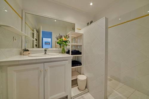 une salle de bain blanche avec un lavabo et un miroir dans l'établissement Sunrise -Swimming-pool-Saint-Tropez center-parking, à Saint-Tropez
