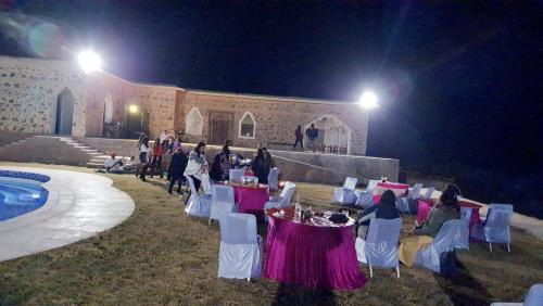 grupa ludzi siedzących przy stolikach w nocy w obiekcie Sariska Kasba A Village Resort w mieście Tehla