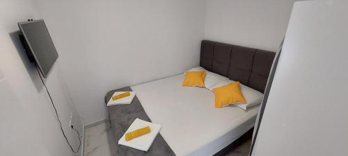 a small bedroom with a bed with yellow pillows at Apartments Amesia with pool, Novalja in Novalja