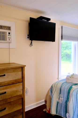 a bedroom with a bed and a television on the wall at The Landings Inn and Cottages at Old Orchard Beach in Old Orchard Beach