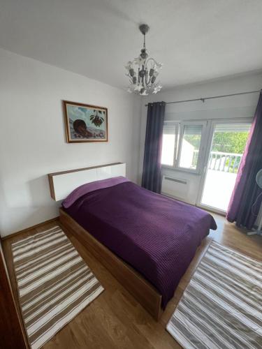 a bedroom with a purple bed and a chandelier at Villa Zak in Blagaj