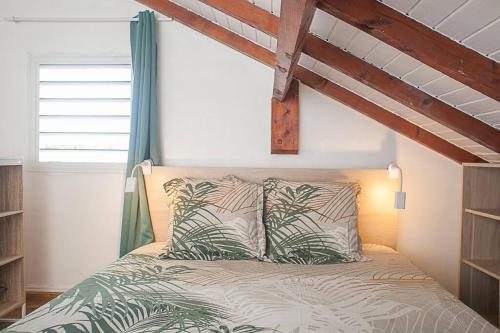 a bedroom with a bed with green and white pillows at Vacances à la plage in Sainte-Anne