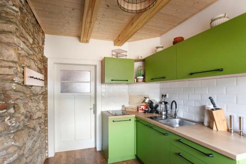 eine Küche mit grünen Schränken und einer Steinmauer in der Unterkunft Chalupa Těšínov in Protiwin