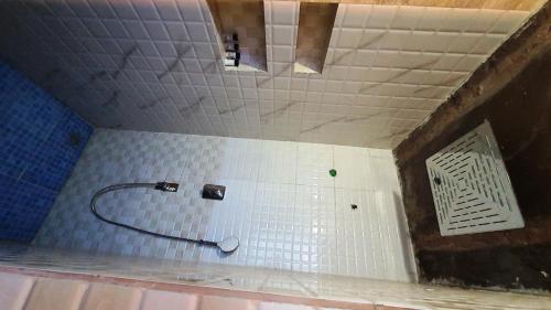 a bathroom with a shower with white tiles at Sariska Kasba - A Village Resort in Tehla