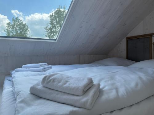 ein Bett mit weißen Handtüchern in einem Zimmer mit Fenster in der Unterkunft Posedy Panský dvůr Telč in Telč