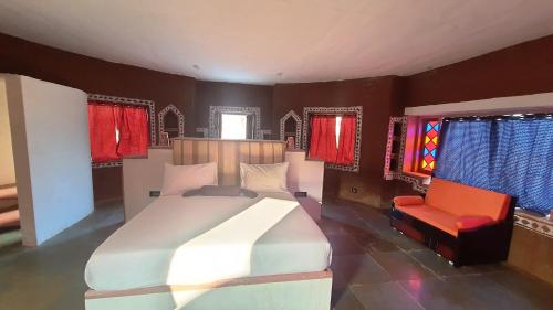 a bedroom with a large bed and a red chair at Sariska Kasba - A Village Resort in Tehla