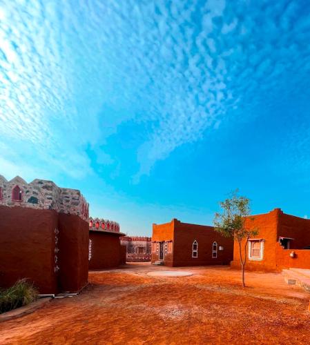 a building in the desert with a blue sky at Sariska Kasba - A Village Resort in Tehla