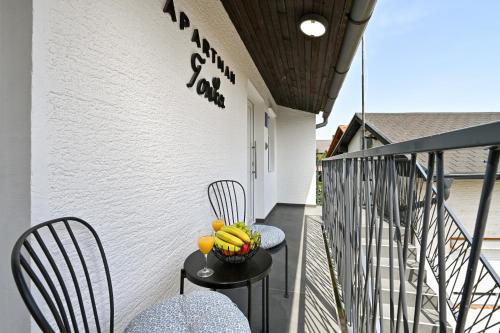 a balcony with two chairs and a bowl of fruit on a table at Tonka studio apartman in Križevci
