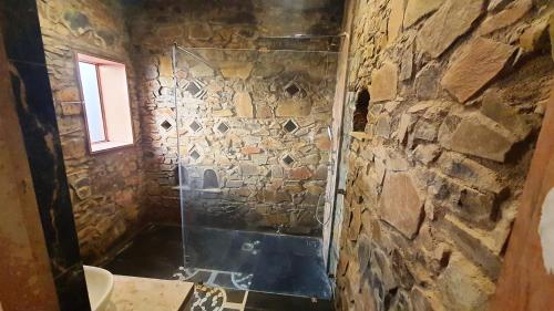 a stone bathroom with a shower with a glass door at Sariska Kasba - A Village Resort in Tehla