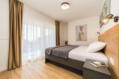 een slaapkamer met een bed en een groot raam bij Villa Petra 1 - private pool in Novalja