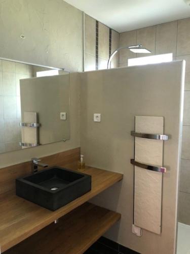 a bathroom with a black sink and a mirror at Les trois pierres in Eguisheim
