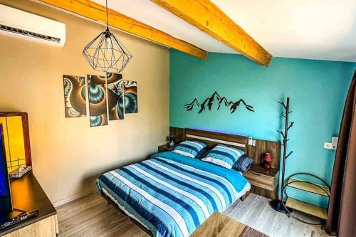 une chambre avec un lit avec un mur bleu dans l'établissement Maisonnette Jacuzzi & Piscine, à Sussargues