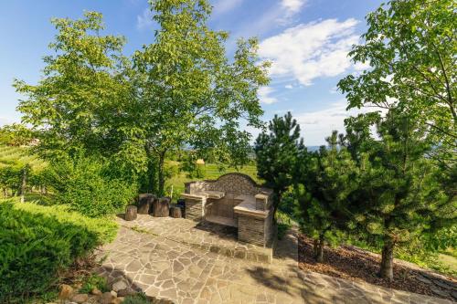 a stone bench in a garden with trees at Cosy Hill Home Rucman With a Breathtaking View in Zgornja Pohanca