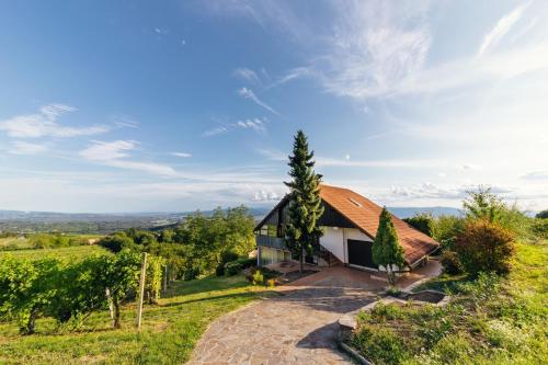 una casa con techo rojo en una colina en Cosy Hill Home Rucman With a Breathtaking View, en Zgornja Pohanca