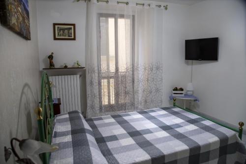 a bedroom with a bed with a checkered blanket and a window at L'Alpino in Sulmona