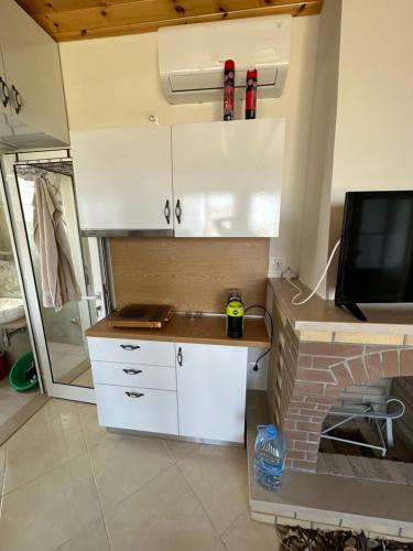 a kitchen with white cabinets and a tv on a wall at Lalzi Rental apartments in Durrës