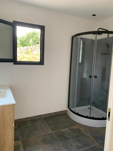 La salle de bains est pourvue d'une douche en verre et d'une fenêtre. dans l'établissement A casetta maison de plain pied, à Sartène