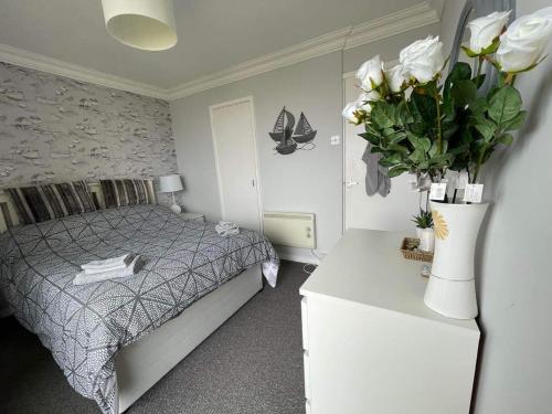 a bedroom with a bed and a vase of flowers at Villa - Sleeps 6 - Pets Ok - Pool - Parking in Lowestoft