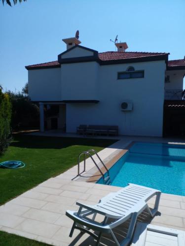 eine Villa mit einem Pool und einem Stuhl in der Unterkunft Luxury villa 3 bedrooms swimming pool in Cesme