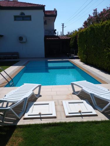 a swimming pool with two lounge chairs next to a house at Luxury villa 3 bedrooms swimming pool in Cesme