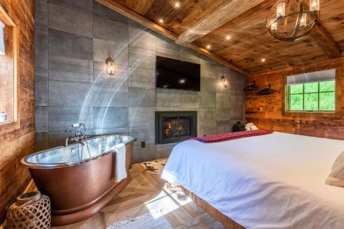 a bedroom with a bed and a tub and a fireplace at The Barnstead Inn in Manchester Center