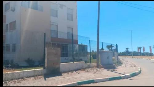 una strada vuota con un edificio e una recinzione di Appartement 2 chambres résidence Sables d’or Tanger a Tangeri