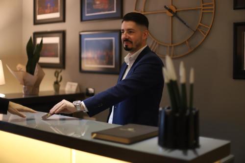 a man in a suit standing at a counter at Hotel Opera in Pristina