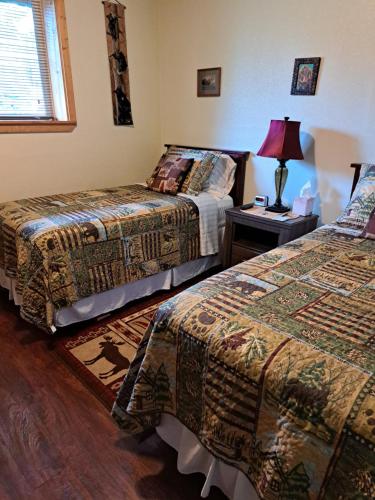 Cette chambre comprend deux lits et une lampe sur une table. dans l'établissement Southern Bluff Bed & Breakfast, à Soldotna