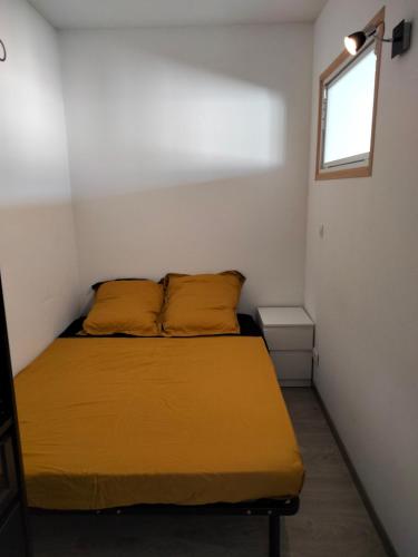 a bedroom with a bed with yellow sheets and a window at Petit cosy in Clermont-Ferrand