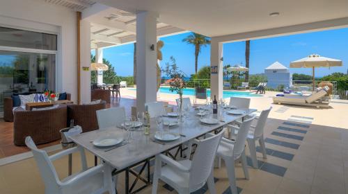 a dining room with a table and white chairs at Grande Dame Villa of Rhodes in Rhodes Town
