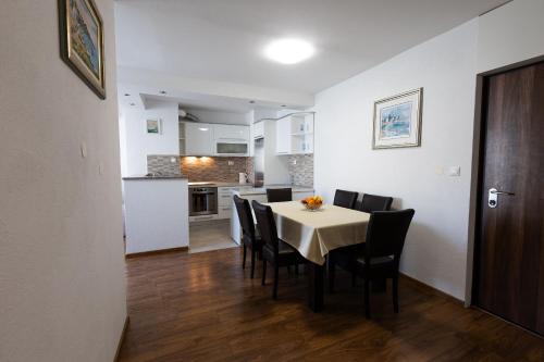 a dining room with a table and chairs and a kitchen at Apartment Srecko in Omiš